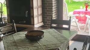 Un coin repas agrémenté d’une cheminée en briques, d’une table dressée avec un set de table, des chaises et un bol.