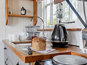 A kitchen with a bread loaf, a coffee maker, and a kettle on the counter.