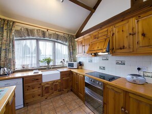 Eine Küche mit Holzschränken, einer Mikrowelle, einem Backofen und einem Spülbecken.