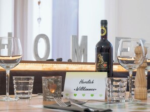 A table set with wine glasses, a bottle of wine, a name card, and a wooden salt shaker. - Casa Mia Milleggapark, (Grächen), 1095 by Interhome (Grächen)