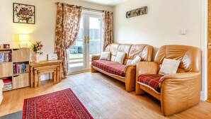 A cozy living room with a leather sofa, a wooden coffee table, a red rug, and a bookshelf. - 2 Bed in Inverness (oc-44481) (Drumnadrochit)