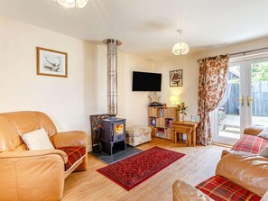 A cozy living room with a fireplace, leather sofas, a red rug, and a television. - 2 Bed in Inverness (oc-44481) (Drumnadrochit)