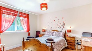 A bedroom with a wooden bed, two bedside tables, a desk, and a window with red curtains. - 2 Bed in Inverness (oc-44481) (Drumnadrochit)