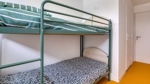 Ein Etagenbett mit gemustertem Lattenrost, einem Metallgestell und einer weißen Tür im Hintergrund.