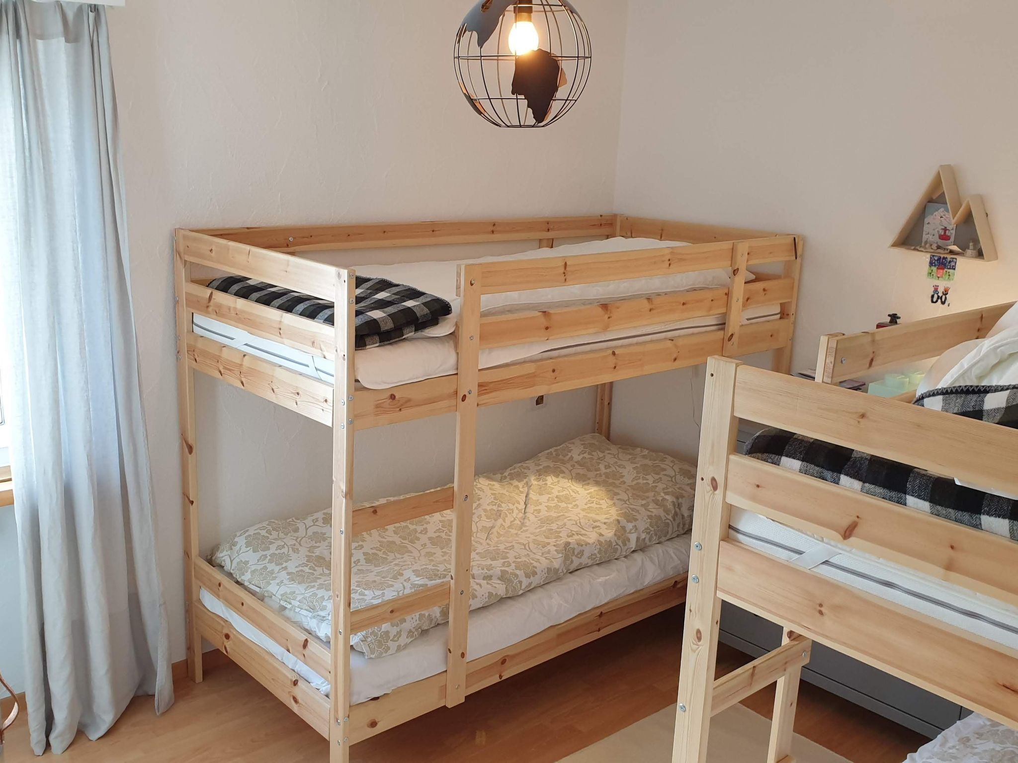 Un lit superposé avec une structure en bois et deux niveaux de couchage, chacun comprenant un oreiller et une couverture.