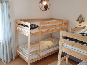 Ein Etagenbett mit Holzrahmen und zwei Schlafstellen, jeweils mit Kissen und Decke.