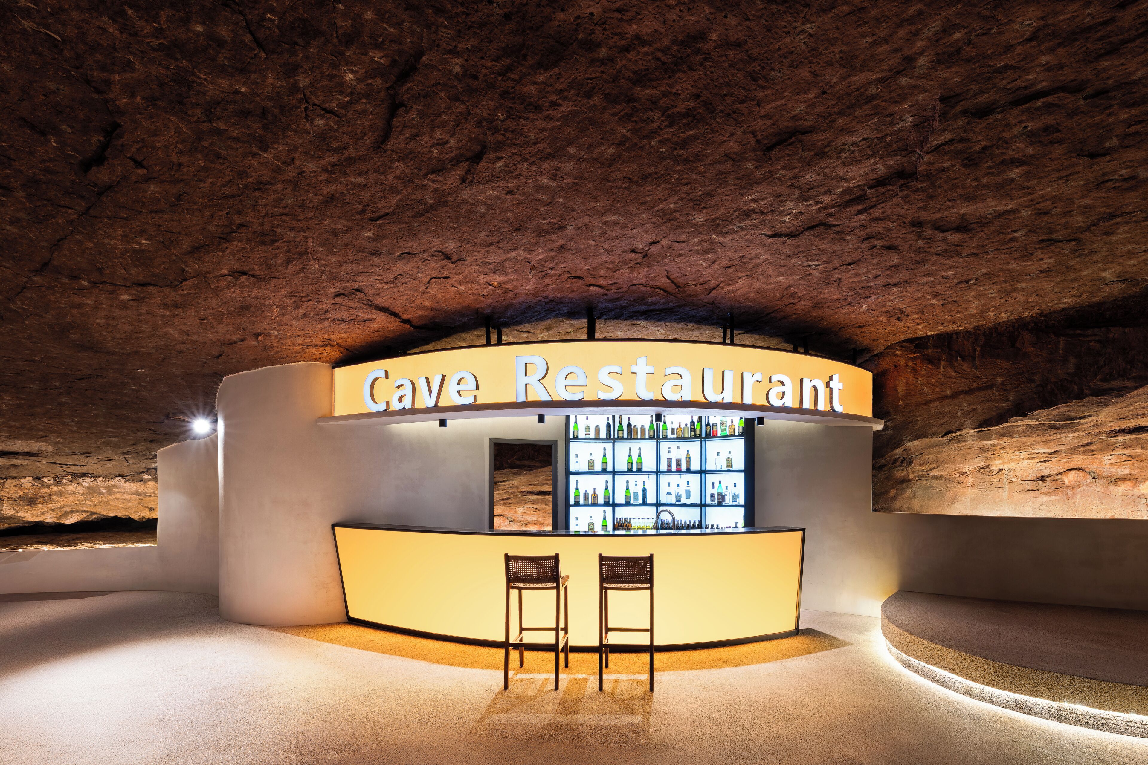 Ein Restaurant in einer Höhle mit Barbereich, Sitzgelegenheiten und einer Flaschenauslage.