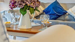 Ein Wohnzimmer mit einer Couch, einem Couchtisch, einer Blumenvase und zwei Gläsern auf dem Tisch.