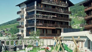 Een hotel met meerdere verdiepingen, balkons, een skipiste en een speeltuin.