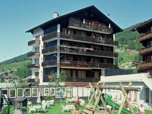 A multi-story hotel with balconies, a ski slope, and a playground. - Touring Cheminée, (Grächen), 1929 by Interhome (Grächen)