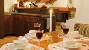 Een eettafel gedekt met witte kommen, wijnglazen en bestek, met een kaars in het midden.
