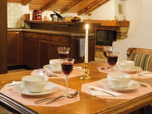 A dining table set with white bowls, wine glasses, and silverware, with a candle in the center. - Touring Cheminée, (Grächen), 1929 by Interhome (Grächen)