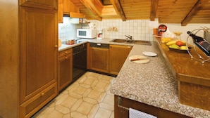 Een keuken met houten kastjes, een magnetron, een spoelbak en een granieten aanrecht.