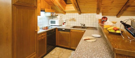 A kitchen with wooden cabinets, a microwave, a sink, and a granite countertop.