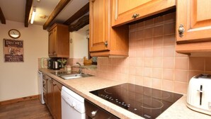 Una cucina con mobili in legno, un piano cottura integrato, una lavastoviglie e un orologio a parete.