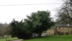 Un tavolo da picnic in una zona erbosa, sullo sfondo un edificio in pietra e alberi.