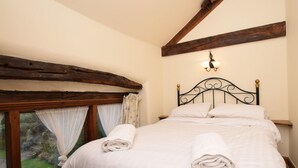 Una camera da letto con un letto, una finestra con tende e un trave in legno al soffitto.