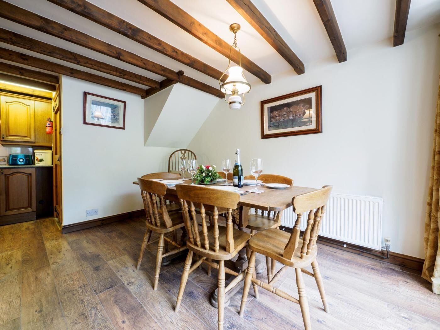 Un espace repas comprenant une table en bois, des chaises et un plafond avec des poutres apparentes.