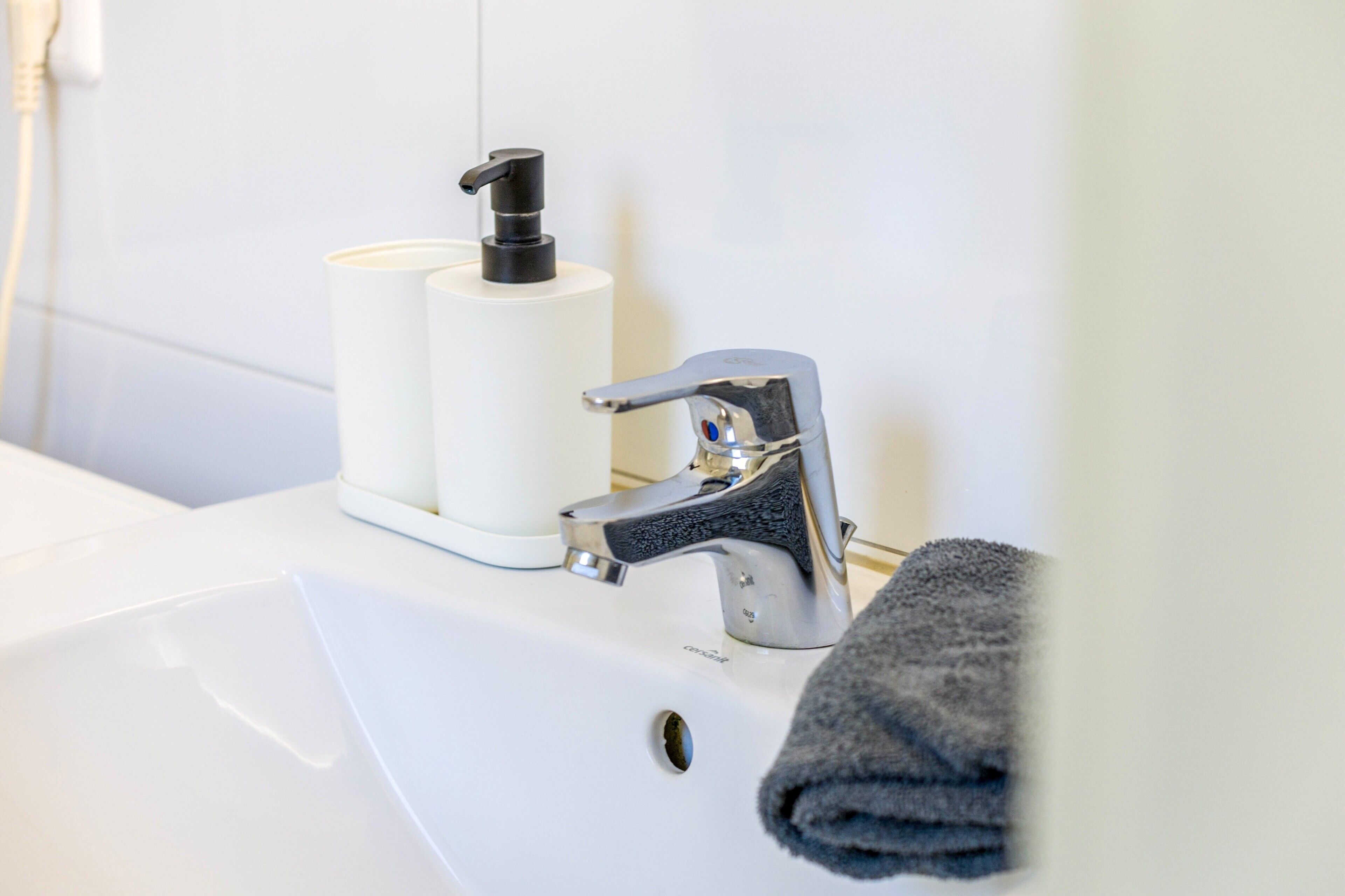 A bathroom sink with a modern faucet and a soap dispenser.