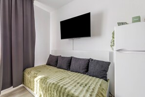 A modern bedroom with a bed, a flat-screen TV mounted on the wall, a white wardrobe, and a green plant. - Apartment 'Rhein Living Business' with Wi-Fi (Duisburg)