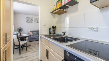 A modern kitchen with a black stove, a sink, and a dishwasher. There is a dining area with a table and chairs.