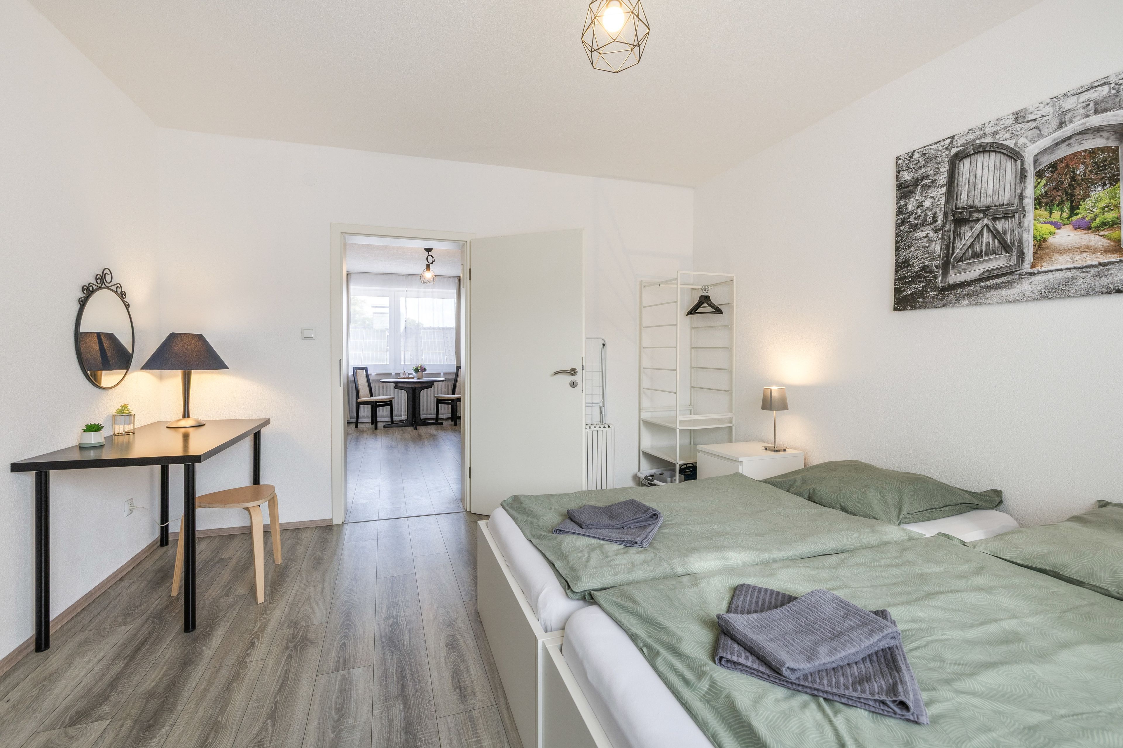 Ein Schlafzimmer mit einem Bett, einem Nachttisch, einer Lampe und einem Bild an der Wand.