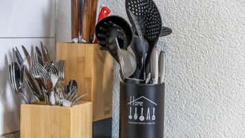 A kitchen utensil holder with various utensils, including a spatula and a grater, and a wooden utensil block.