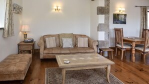 Un salon chaleureux avec un canapé, une table basse, un banc, une table à manger avec des chaises et un mur d’accent en pierre.