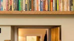 A bookshelf with various books, a wooden staircase, and a doorway leading to another room. - 4 Bed in High Peak (oc-pk630) (Chapel-en-le-Frith)
