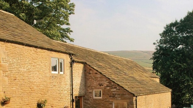 A stone building with a sloped roof, a small window, and a door. - 4 Bed in High Peak (oc-pk630) (Chapel-en-le-Frith)