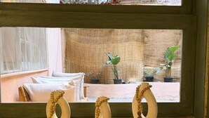 Ein Fenster mit Blick auf einen Innenhof, eine Holzablage mit drei dekorativen Vasen und ein Blick auf ein Gebäude im Freien.