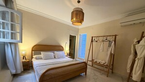 Ein Schlafzimmer mit einem Bett, einer Nachttischlampe, einer Pendelleuchte, einem Holzschrank und einem Handtuchhalter.