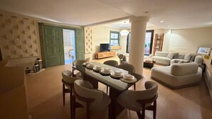 Ein Essbereich mit einem Tisch für vier Personen, einer Couch und einem Fernseher in einem Wohnzimmer.