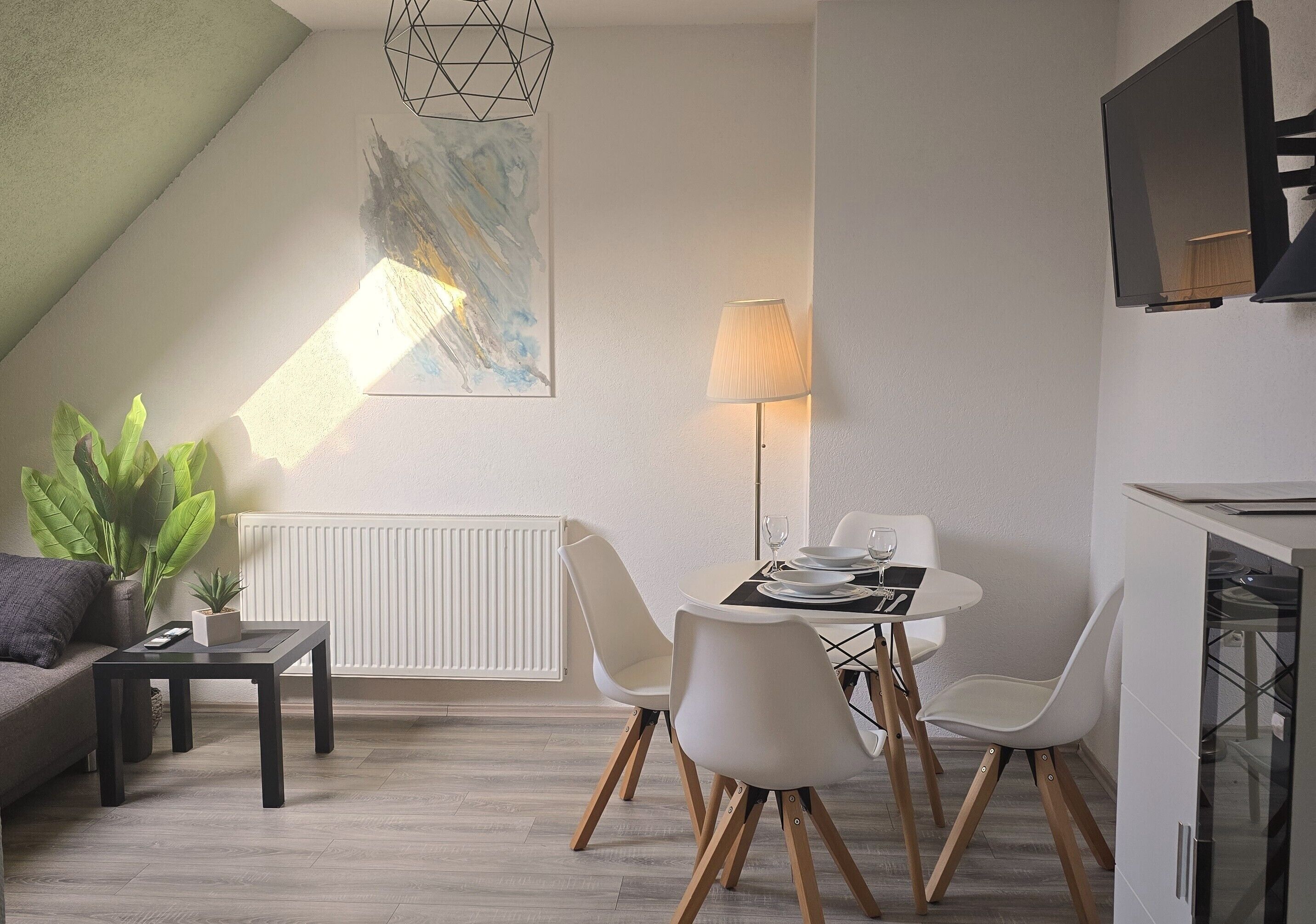 Uma sala de estar moderna com área de jantar, sofá, mesa de centro, luminária e radiador.