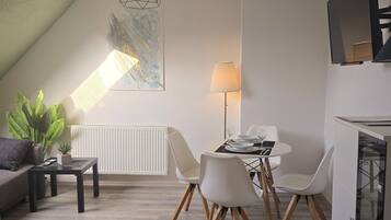 Uma sala de estar moderna com área de jantar, sofá, mesa de centro, luminária e radiador.