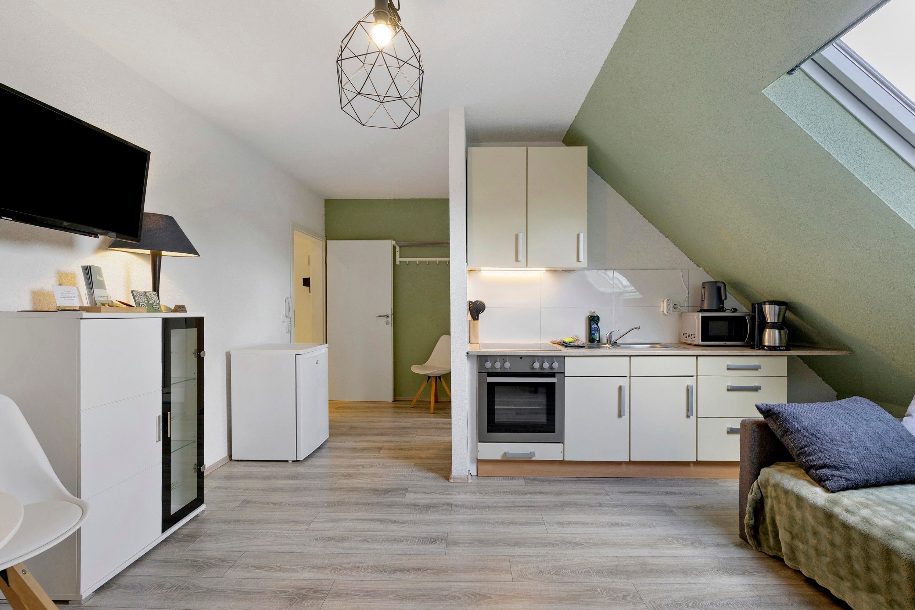 A compact kitchen with a microwave, stove, and a small refrigerator.