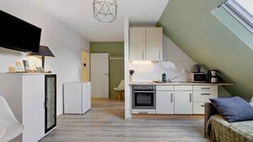 A compact kitchen with a microwave, stove, and a small refrigerator.