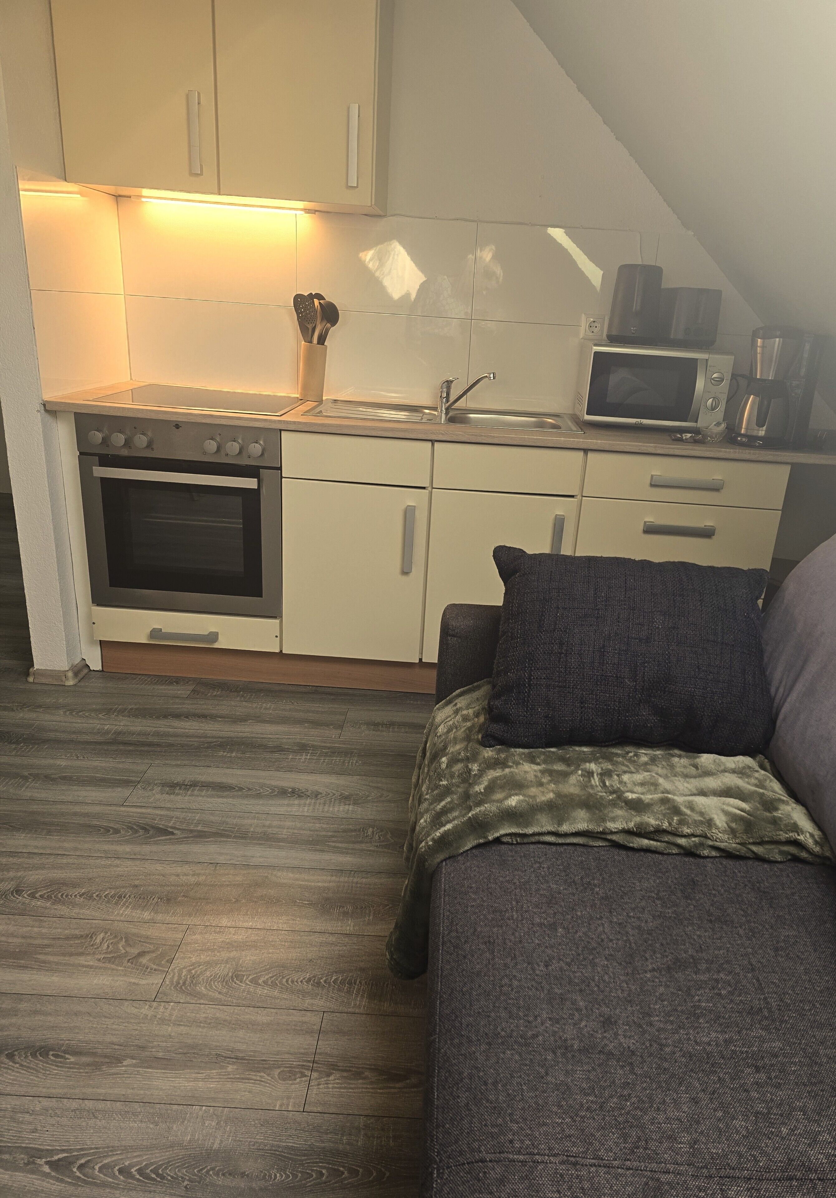 A compact kitchenette with a microwave, stove, and sink.