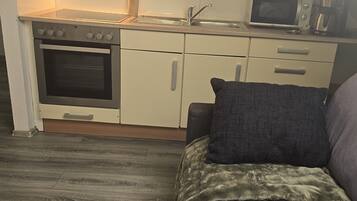 A compact kitchenette with a microwave, stove, and sink.