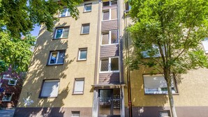 A multi-story residential building with a central entrance, windows, and a tree in front. - Apartment 'Flora Modern Living' with Wi-Fi (Duisburg)