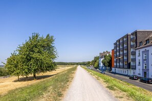 A road leading to a modern apartment building with a clear sky.