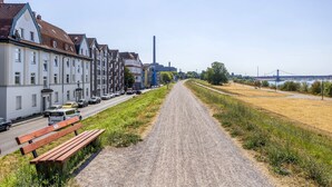 A gravel path leading to a row of residential buildings with a bench on the side. - Apartment 'Flora Modern Living' with Wi-Fi (Duisburg)