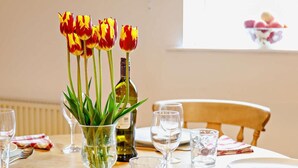 A dining table with a vase of tulips, wine glasses, and a bottle of wine. - 2 Bed in Bakewell (oc-44607) (Little Longstone)