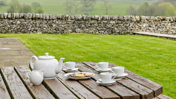 A picnic setup with a stone wall, grassy field, and a stone pathway. - 2 Bed in Bakewell (oc-44607) (Little Longstone)