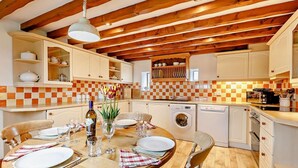 A kitchen with wooden beams, a dining table set for four, and a washing machine. - 2 Bed in Bakewell (oc-44607) (Little Longstone)