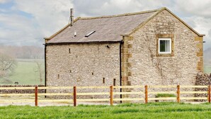 A stone building with a sloped roof, a small window, and a wooden fence in front. - 2 Bed in Bakewell (oc-44607) (Little Longstone)