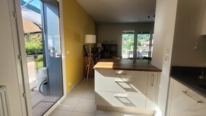 Uma cozinha com armários brancos, bancada de madeira e vista para o exterior.
