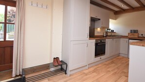 Eine Küche mit weißen Schränken, einer Holz Arbeitsplatte, einem Einbauofen und einem Fenster mit Vorhängen.