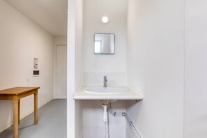 A bathroom with a white sink, a mirror above it, and a wooden table in the adjacent room. - Room with Shared Terrace and Wi-Fi, 10 Minutes from the Beach (Mudaison)
