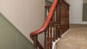 A wooden staircase with a handrail and a carpeted landing.